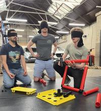 groups of students work to build a chair blindfolded 